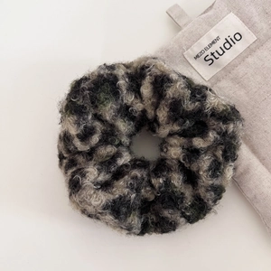 Close-up of fluffy leopard print scrunchie with soft woolly texture in dark green and grey