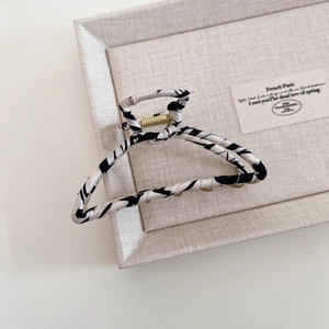 Close-up of zebra pattern fabric wrapped metal hair claw clip on beige display tray