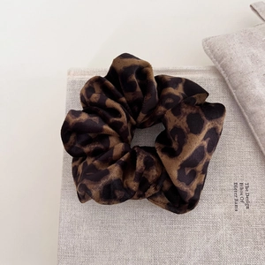 Close-up of leopard print velvet hair scrunchie with soft fabric texture and elegant pattern