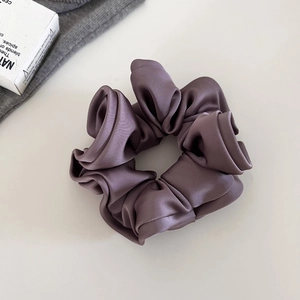 Détail du chouchou élégant en satin violet poudré avec un fini brillant et des plis soyeux