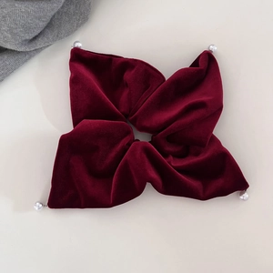 Macro shot of deep red velvet scrunchie featuring elegant faux pearl accents on corners