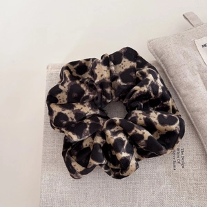 Detail of premium leopard print velvet scrunchie on vintage book with warm natural lighting