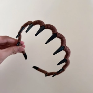 Detailed close-up of a brown yarn-wrapped wavy headband with anti-slip black teeth combs