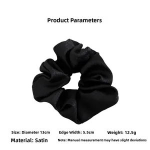 Detail view of black satin scrunchie with 13cm diameter and 5.5cm width specs