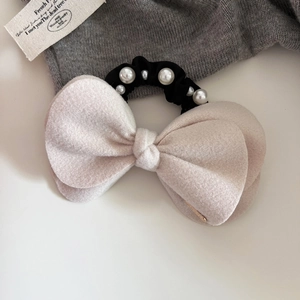Close-up of wool texture pink bow hair tie featuring glossy pearls and metal logo detail