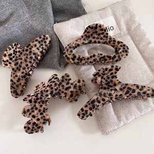 Retro leopard print acetate hair claws set on grey sweater and beige fabric bag