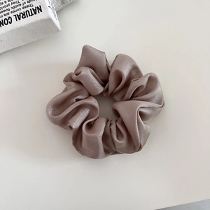 Detail of premium champagne satin scrunchie with silky texture and elegant folds