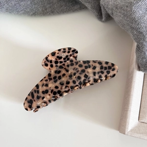 Detail of leopard print acetate hair claw clip showing glossy finish and grip teeth