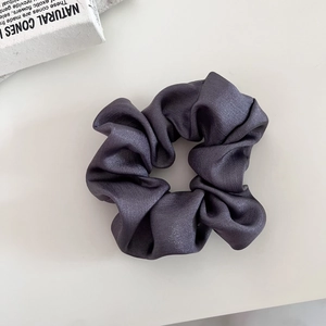 Detail of elegant dark grey satin scrunchie with glossy silk texture and pleated design