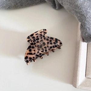 Detailed macro view of the glossy leopard print acetate hair claw with golden lettering
