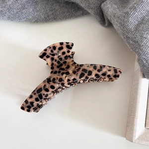 Macro detail of the smooth leopard print acetate claw clip with a glossy finish texture