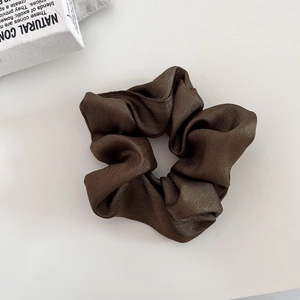 Detailed close-up of dark brown satin scrunchie with metallic shimmer and pleated texture