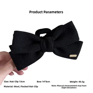 Detailed view of 13cm wool bow claw clip with gold emblem and soft flocked texture