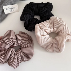 Close-up of pleated scrunchies set in black, cream and lilac with soft ribbed texture