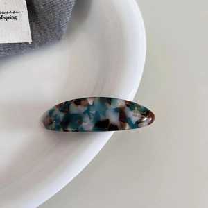 Detailed close-up of marble pattern acetate hair clip with golden France Handmade mark