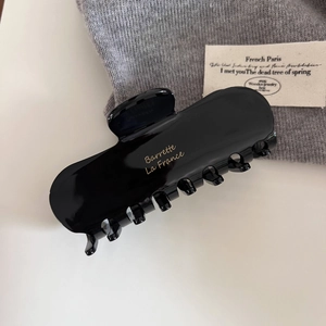 Macro detail of glossy black square hair claw clip with gold Barrette La France lettering