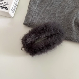Vue détaillée de la texture en fausse fourrure peluche gris foncé sur un étui AirPods