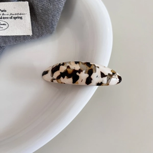 Detail of oval acetate spring hair clip with tortoiseshell texture and handmade mark