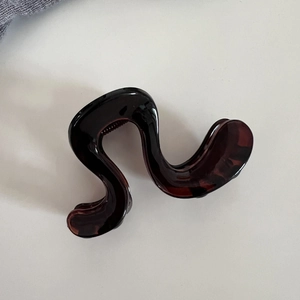 Détail macro d'une pince à cheveux ondulée motif écaille avec finition polie et dents