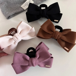 Flat lay of wool bow hair claws in black, beige, brown and purple with gold labels