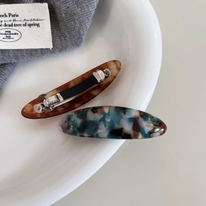 Retro oval acetate spring hair clips in tortoiseshell and marble patterns with gold lettering