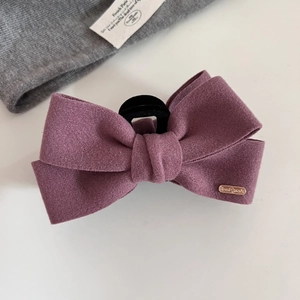 Detailed macro view of purple wool bow hair claw clip with golden handmade metal logo