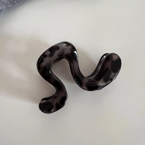 Détail de la pince à cheveux ondulée motif écaille grise montrant le ressort en métal