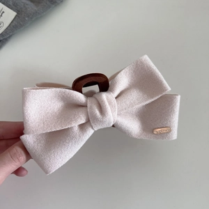 Detailed view of light pink suede bow hair claw clip with golden Handmade metal tag