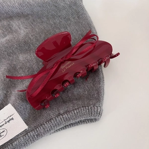 Elegant wine red hair claw clip with thin ribbon and gold lettering on grey knit fabric