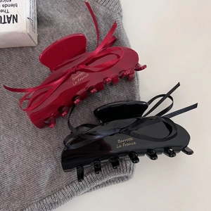 Detail view of burgundy and black hair claws with ribbon bows and gold lettering