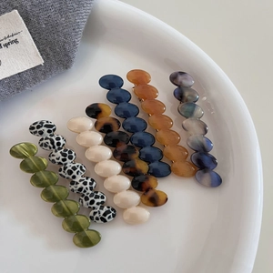 Elegant wavy acetate hair clips in multiple colors displayed on a white ceramic tray