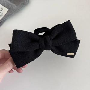 Detail of wool fabric bow hair claw clip with elegant gold rectangular metal logo