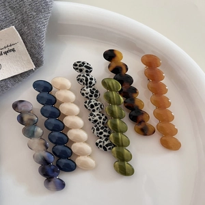 Set of 6 textured acetate oval hair clips in assorted colors on a ceramic dish