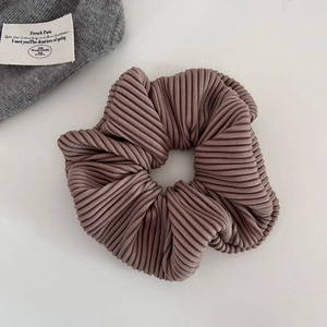 Close-up of brown pleated scrunchie with fine vertical stripe texture and elastic fabric