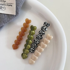 Set of four acetic acid heart hair clips in amber, green, spotted, and cream colors