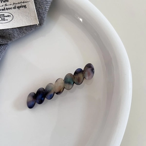 Detail of elegant acetate resin marble beads on a golden alloy hair clip for women