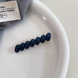Detailed view of elegant navy blue acetate oval beads on a golden metal hair clip