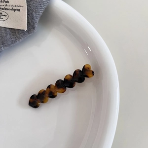 Detail of tortoise shell heart hair clip with seven units on a white ceramic plate