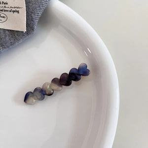 Detail of gradient acetate hair clip featuring seven connected heart shapes in blue and purple