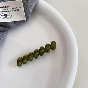 Detail of an olive green acetate bead hair clip featuring translucent oval resin beads