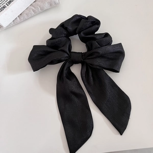 Dettaglio di un elegante elastico in raso nero con fiocco e nastri scintillanti