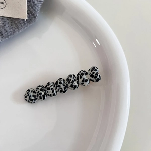 Detailed view of acetic acid heart-shaped hair clip with cow pattern on white plate