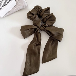 Dettaglio dello scrunchie in raso caffè scuro con lunghi nastri su sfondo bianco