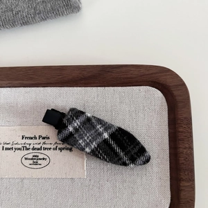 Detail of classic grey plaid fabric hair clip with vintage texture on a wooden tray
