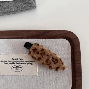 Close-up of a leopard print plush hair clip on a wooden tray with soft faux fur texture