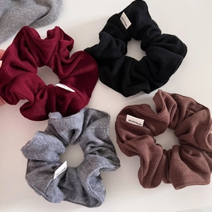 Flat lay of knit scrunchies in wine red, black, grey and brown with Hand Made labels
