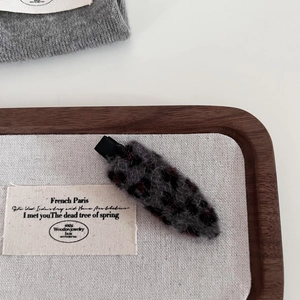 Close-up of leopard print wool hairpin with soft texture and black duckbill clip detail