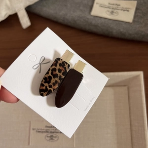 Dettaglio di fermagli per capelli leopardati e marrone scuro con clip a becco dorata
