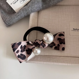 Vintage leopard print bow hair tie with pearls on an aesthetic minimalist tray