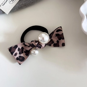Detailed view of leopard print bow hair scrunchie with elegant faux pearl accents
